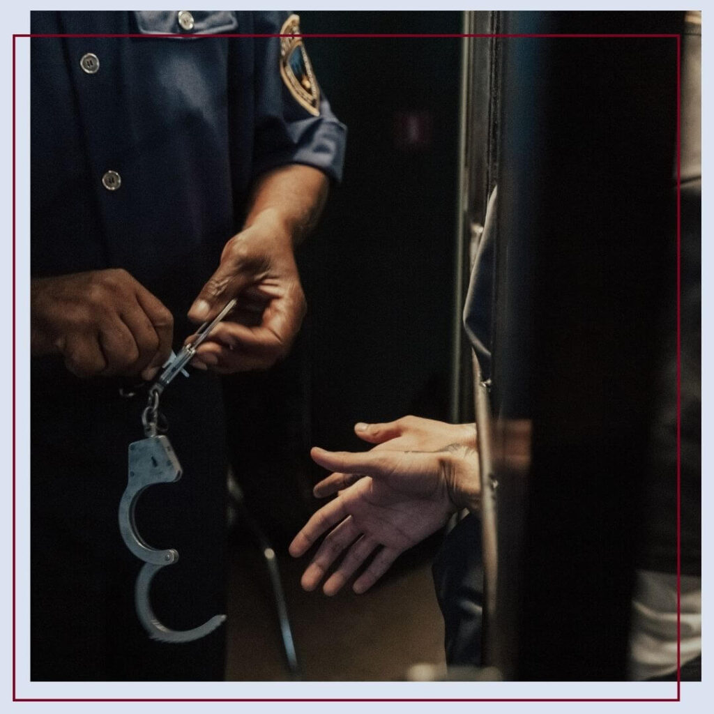 police officer holding handcuffs in front of prisoner